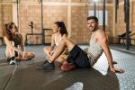 Man With Female Athletes Resting At Gym